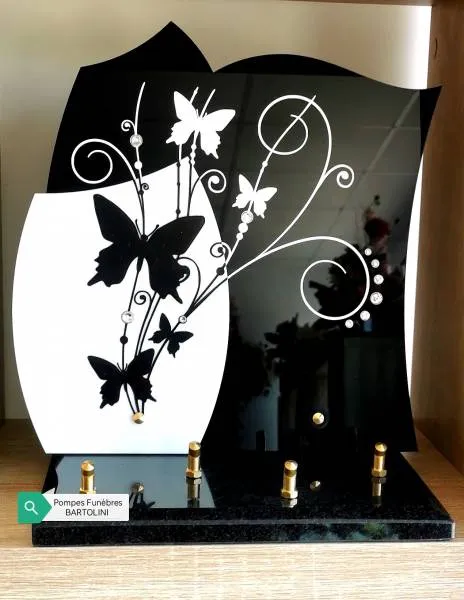 Plaque funéraire en granit noir et blanc illustrée de papillons en envol