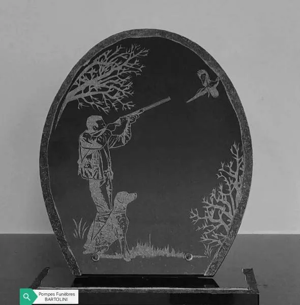 Plaque funéraire ovale en granit noir gravée d'un chasseur visant un oiseau