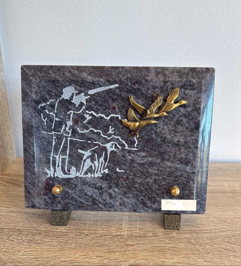Plaque funéraire en granit gravée d'un chasseur et son chien avec branche d'olivier en bronze