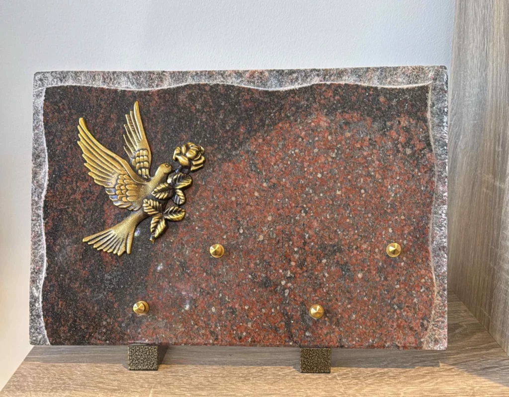 Plaque funéraire en granit rouge ornée d'une colombe en bronze en envol