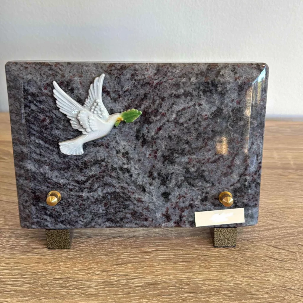 Plaque funéraire en granit bleu avec figurine de colombe blanche tenant un rameau