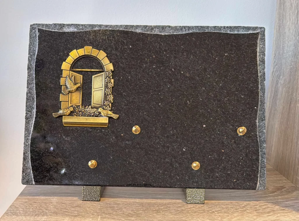 Plaque funéraire en granit noir ornée d'une fenêtre ouverte avec colombes