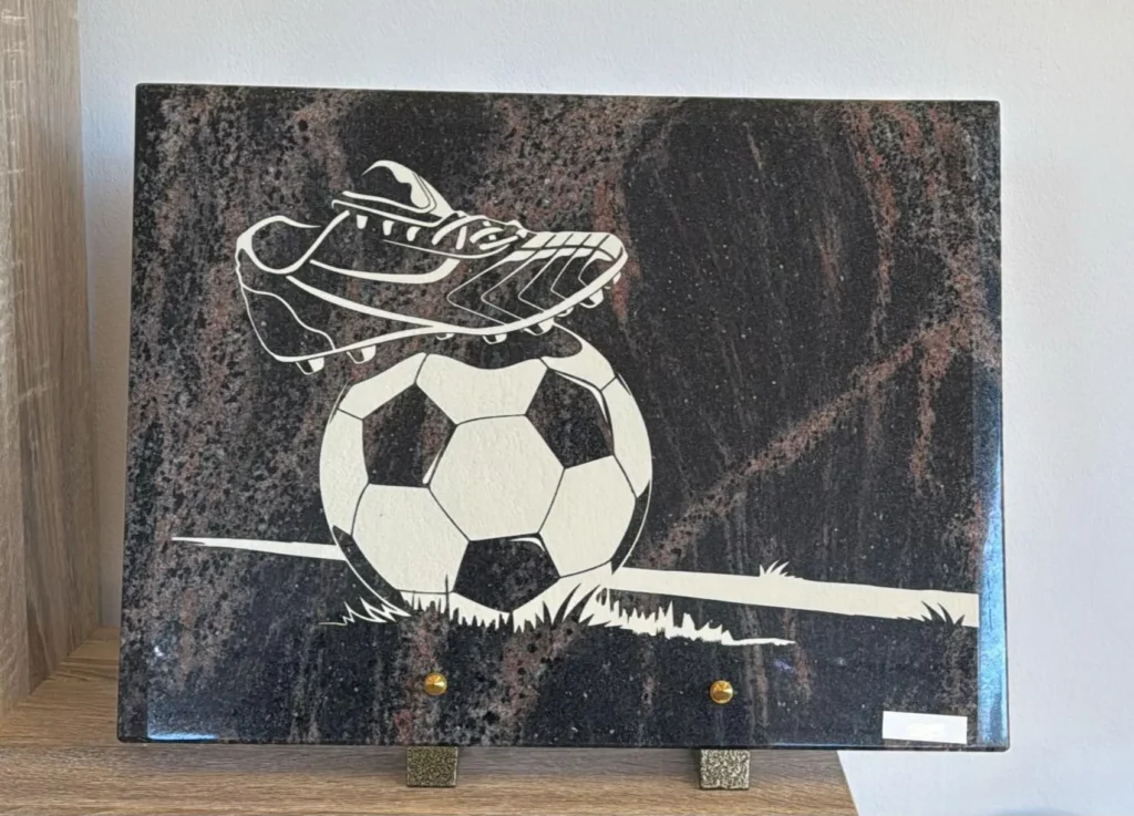 Plaque funéraire en granit gravée d'une chaussure et d'un ballon de football