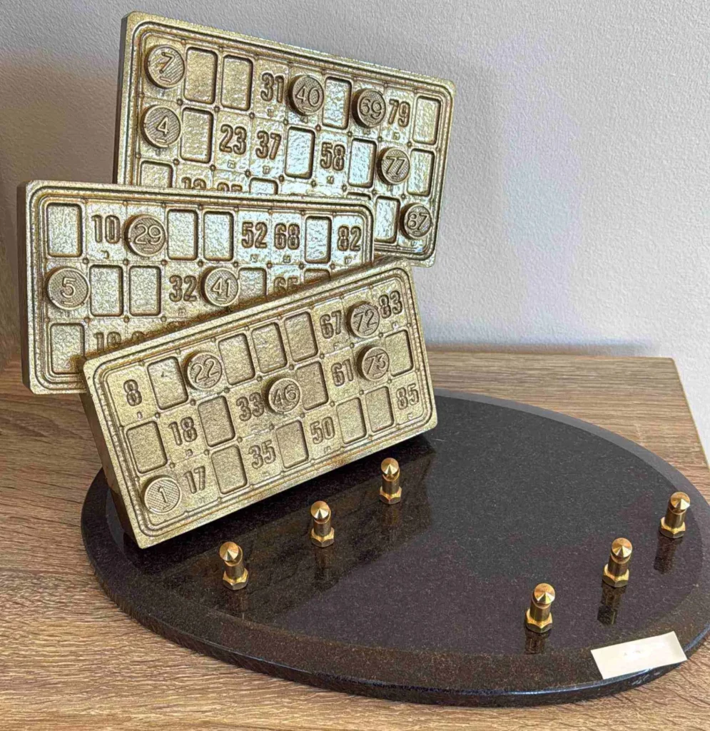 Plaque funéraire avec figurines de cartes de loto en bronze sur socle en granit