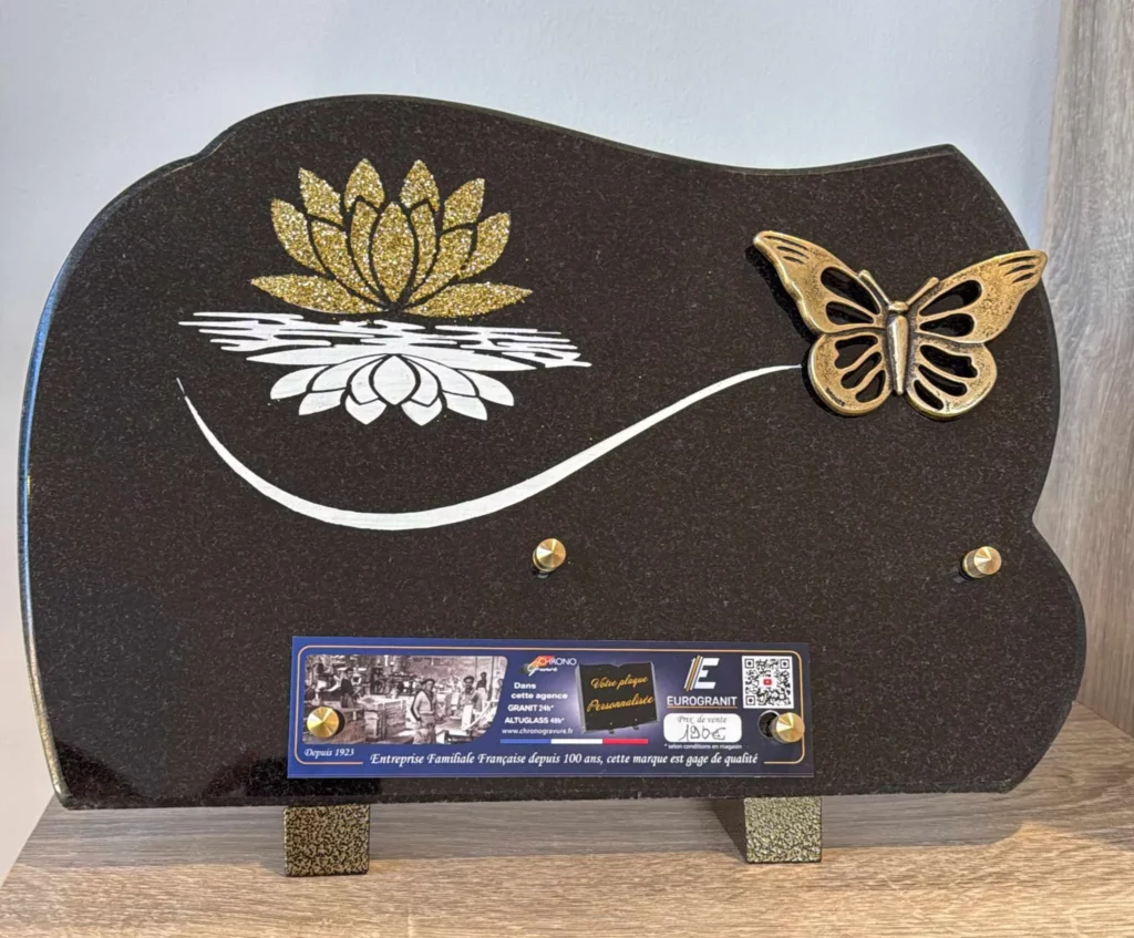 Plaque funéraire en granit noir décorée d'un nénuphar gravé et d'un papillon en bronze