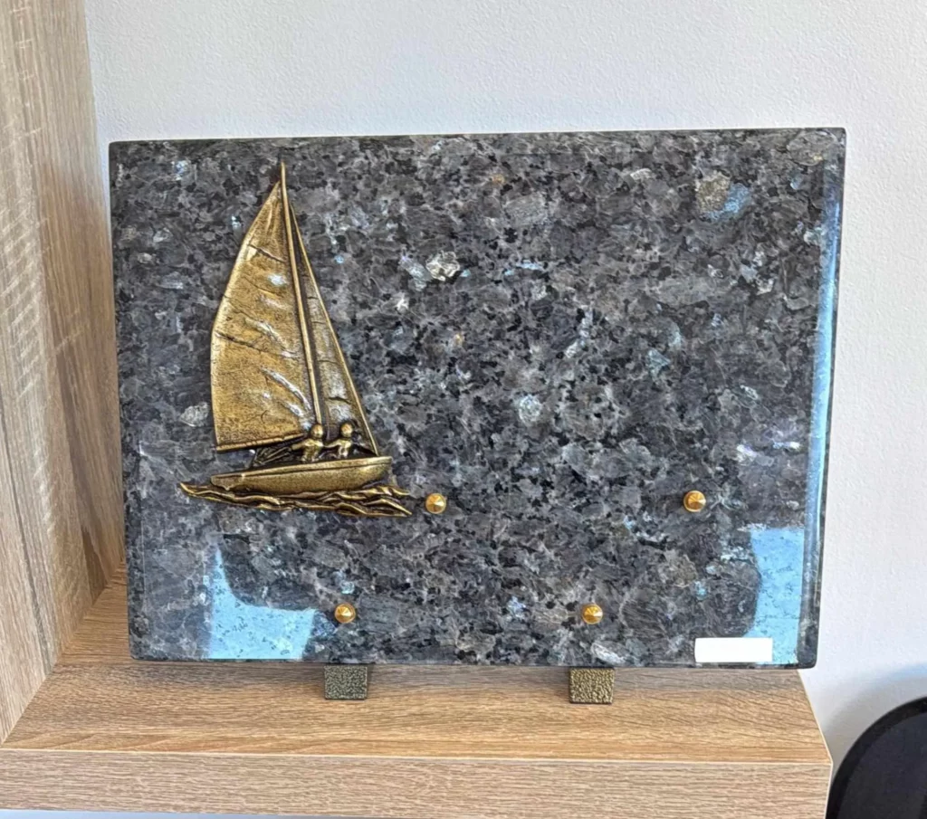 Plaque funéraire en granit bleu Labrador ornée d'un voilier en bronze