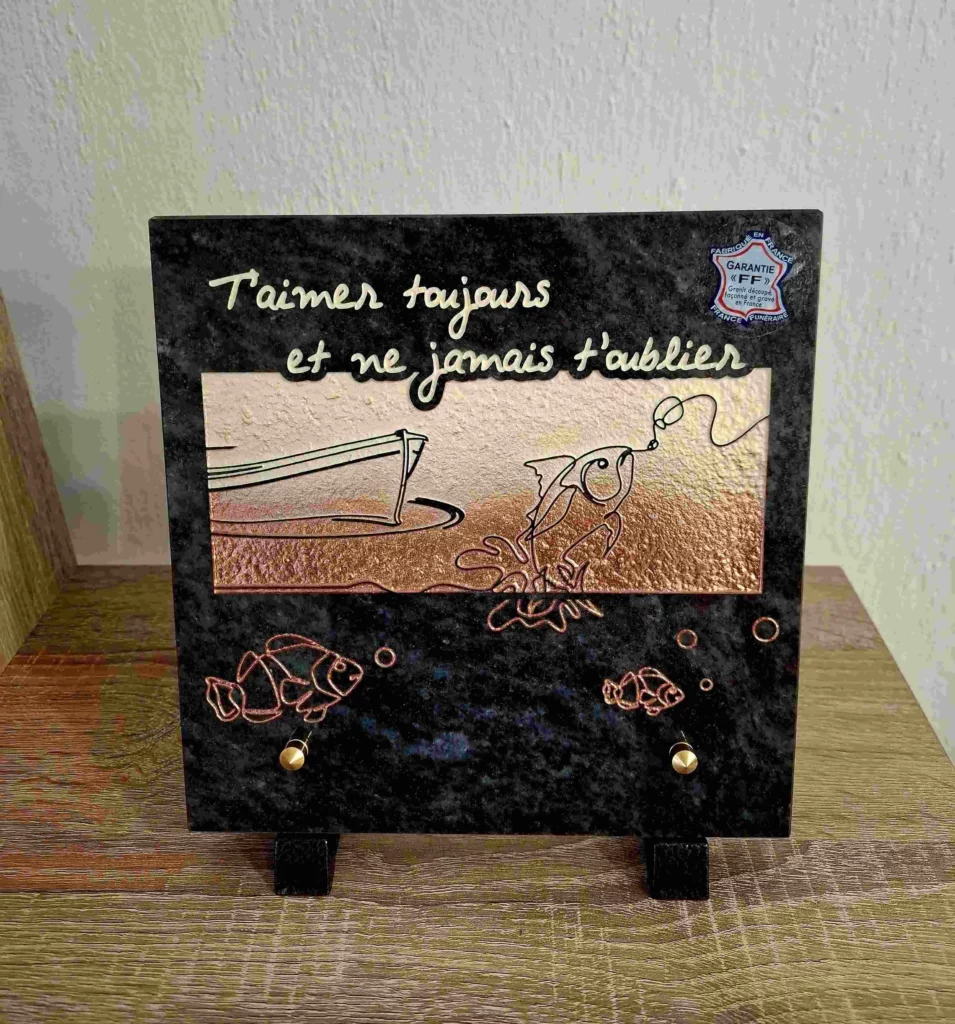 Plaque funéraire en granit bleu avec illustration de bateau de pêche et poissons