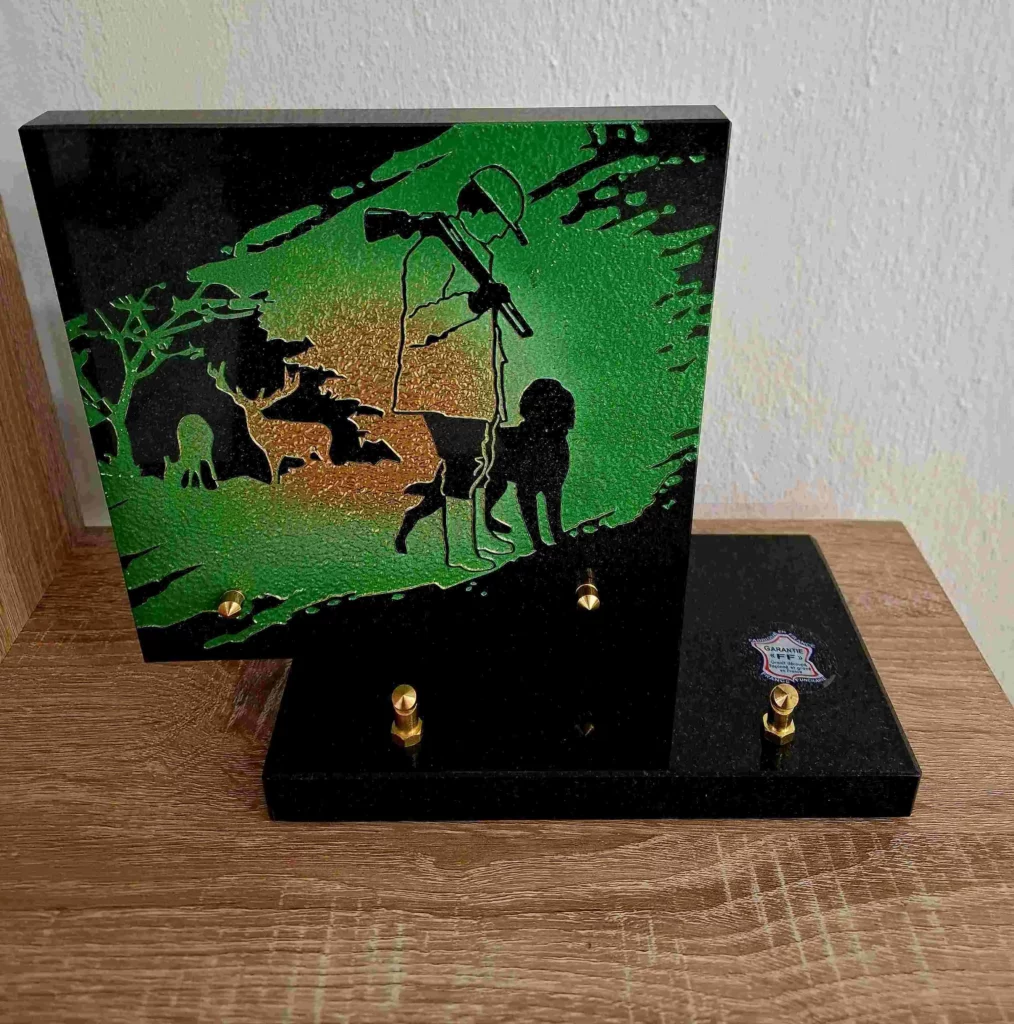 Plaque funéraire en granit vert et noir illustrée d'un chasseur avec son chien en forêt