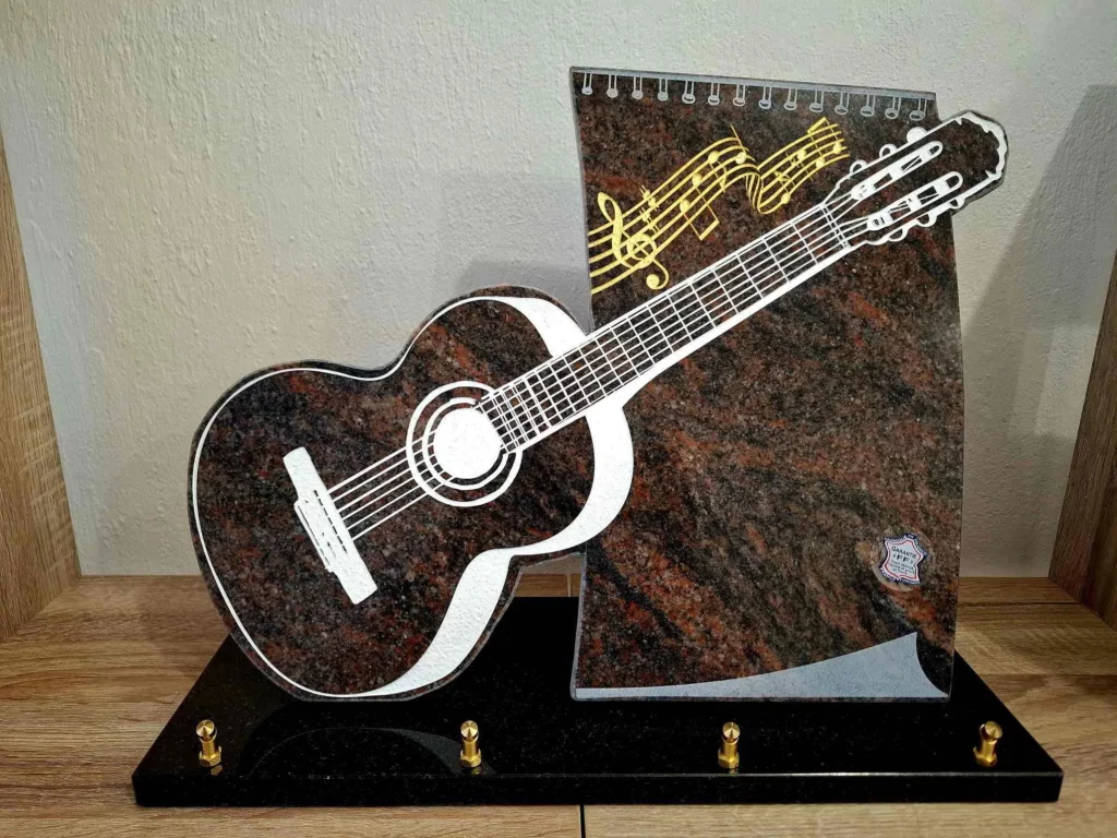 Plaque funéraire en granit avec guitare sculptée en relief et portée de musique
