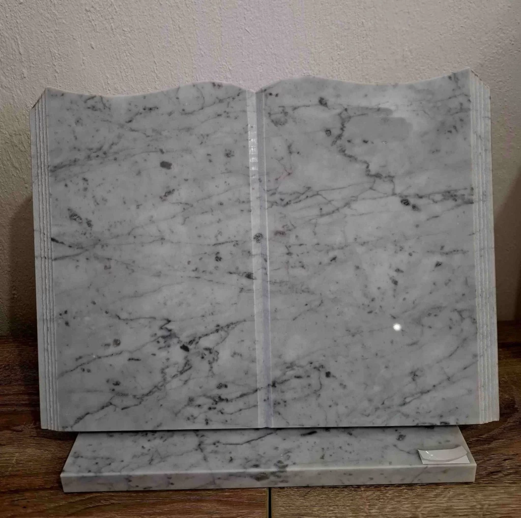 Plaque funéraire en marbre blanc veiné découpée en livre ouvert