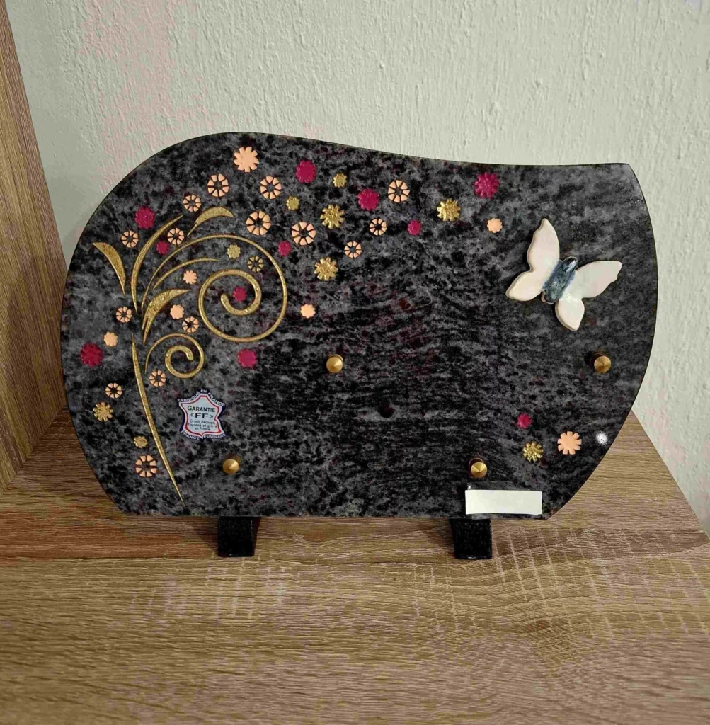 Plaque funéraire wavy en granit noir illustrée de motifs floraux et papillon