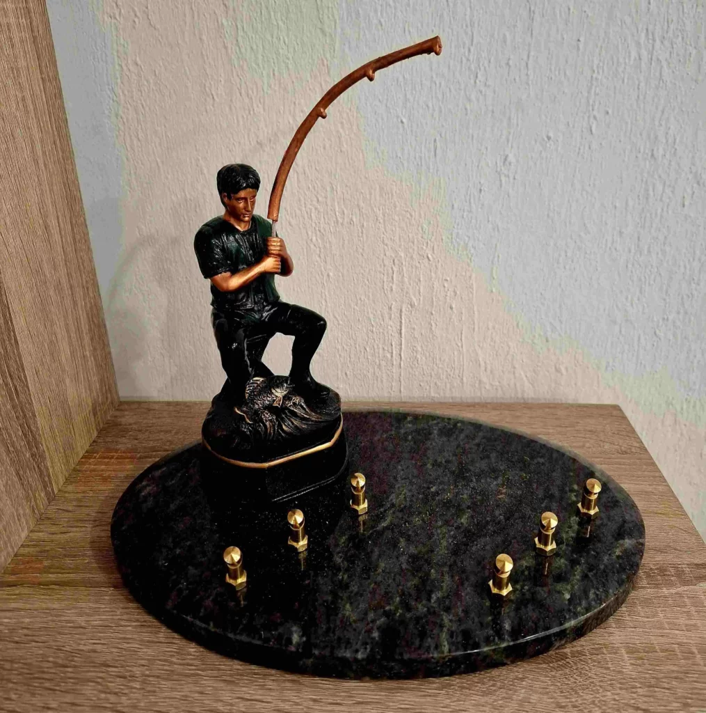 Plaque funéraire en granit avec figurine de pêcheur à la ligne sur socle ovale