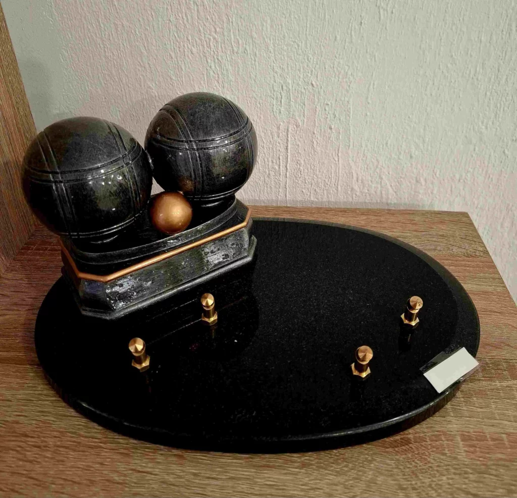 Plaque funéraire en granit noir avec sculpture de boules de pétanque et cochonnet