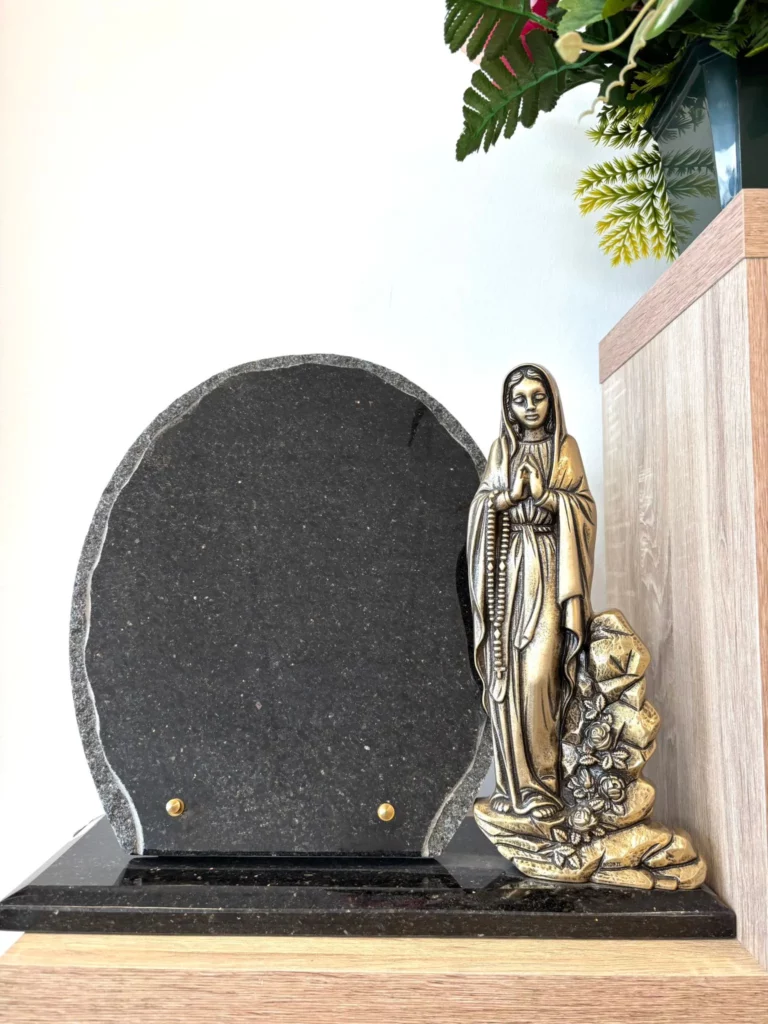Plaque funéraire en granit sombre ornée d'une figurine de la Vierge Marie en bronze