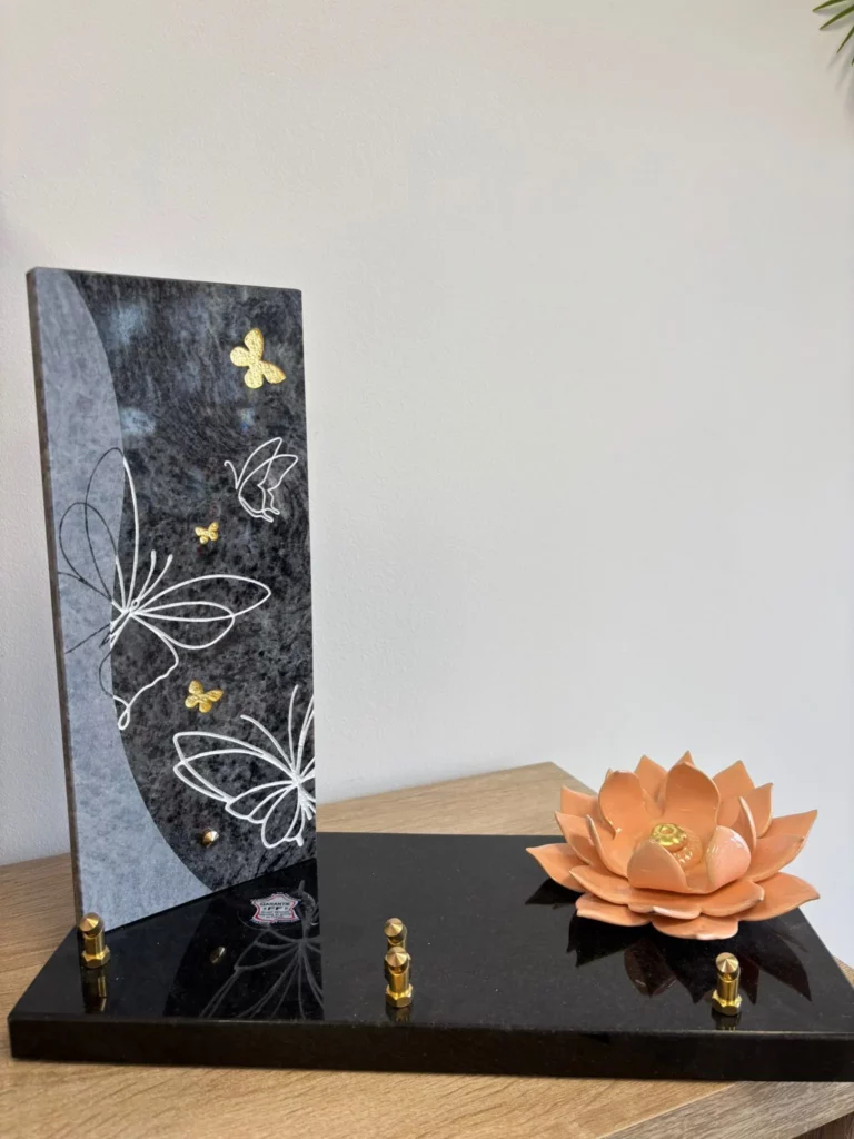 Plaque funéraire en granit noir avec papillons gravés et fleur de lotus en céramique