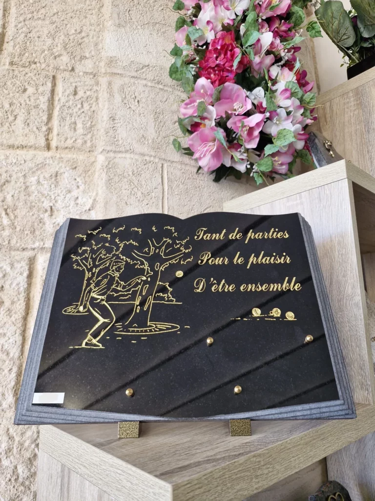 Plaque funéraire en granit noir en forme de livre gravé de joueurs de pétanque