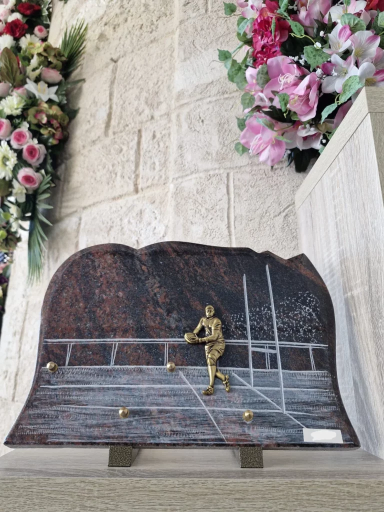 Plaque funéraire sur socle en granit découpé représentant un joueur sur un terrain de rugby