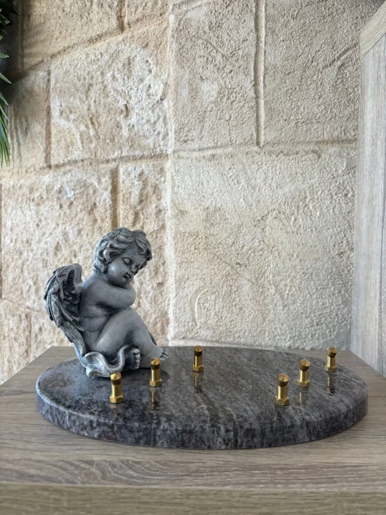 Plaque funéraire ronde en granit sombre ornée d'une statuette d'ange en résine