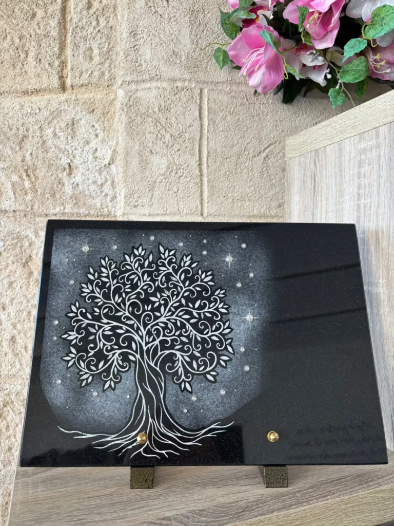 Plaque funéraire rectangulaire en granit noir gravée d'un arbre de vie et ciel étoilé